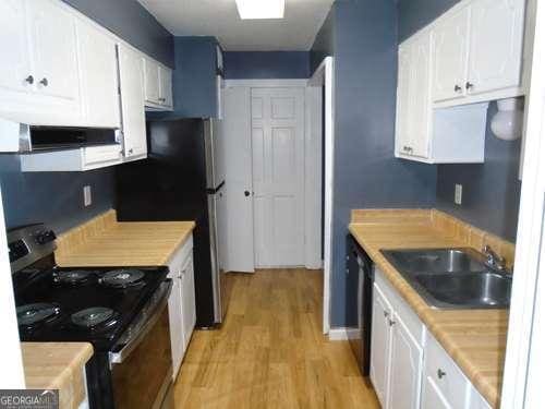 kitchen with sink, white cabinets, light hardwood / wood-style floors, and electric stove