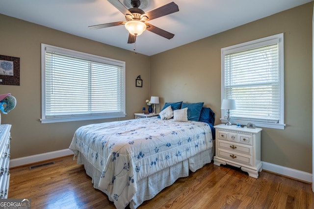 bedroom with ceiling fan, multiple windows, and wood-type flooring