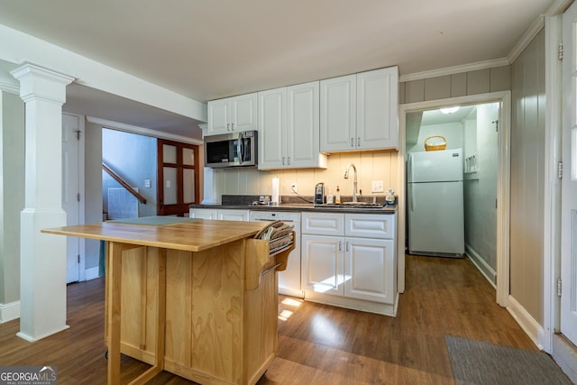 kitchen featuring fridge, sink, white cabinets, a kitchen island, and decorative columns