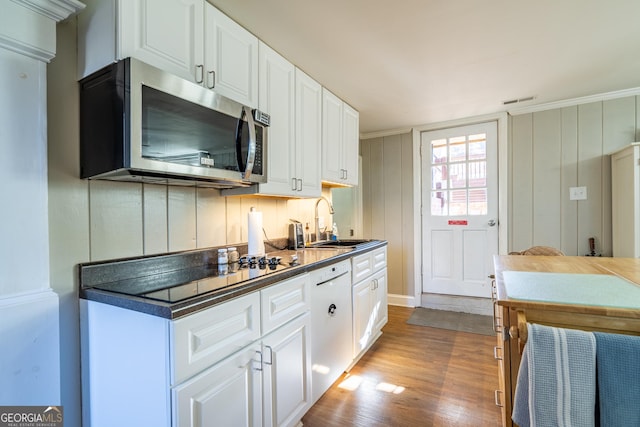 kitchen with white dishwasher, sink, white cabinets, and light wood-type flooring