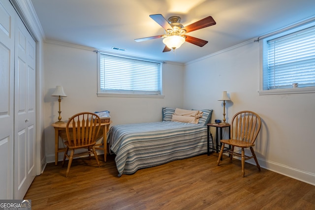 bedroom featuring ceiling fan, a closet, dark hardwood / wood-style flooring, and ornamental molding