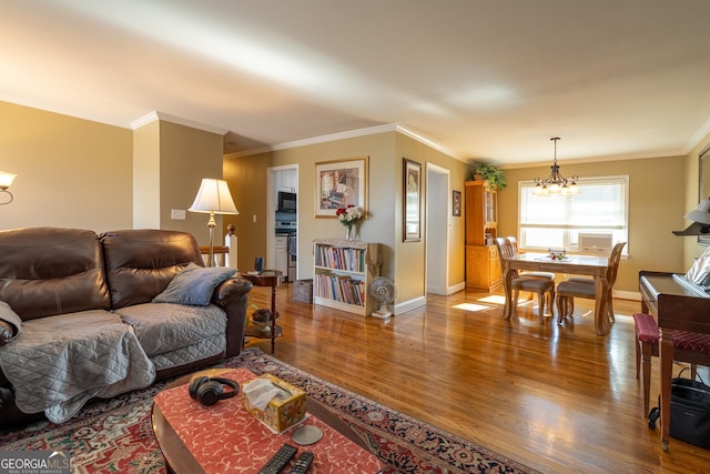 living room with wood-type flooring, crown molding, and an inviting chandelier