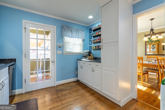 interior space with light wood-type flooring, white cabinetry, pendant lighting, and ornamental molding