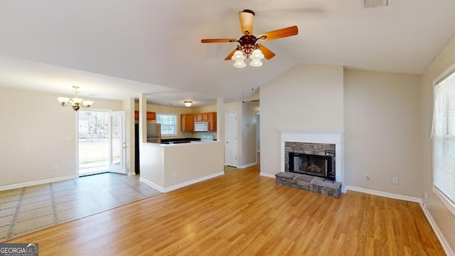 unfurnished living room featuring a fireplace, light hardwood / wood-style floors, ceiling fan with notable chandelier, and lofted ceiling