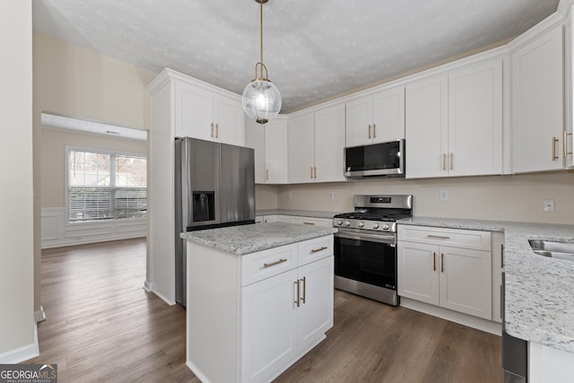 kitchen with pendant lighting, light stone countertops, white cabinetry, and stainless steel appliances