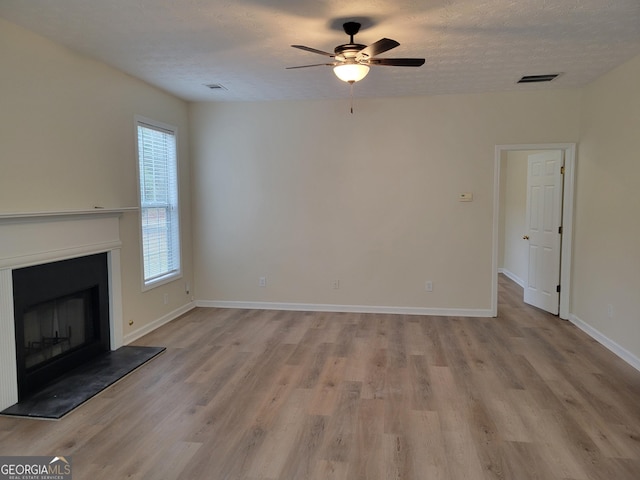 unfurnished living room featuring ceiling fan, a textured ceiling, and light wood-type flooring