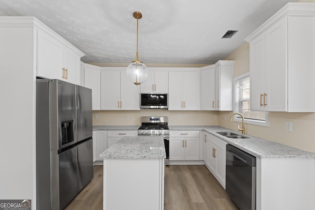 kitchen with decorative light fixtures, sink, white cabinets, a center island, and stainless steel appliances