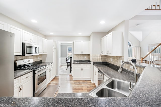 kitchen with white cabinetry, stainless steel appliances, sink, and tasteful backsplash