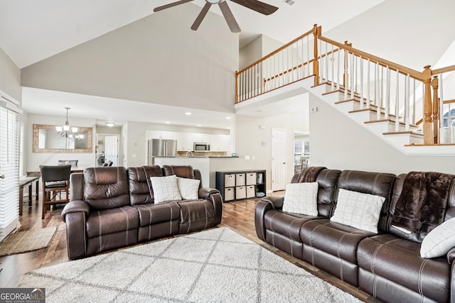 living room featuring ceiling fan with notable chandelier, high vaulted ceiling, and hardwood / wood-style floors