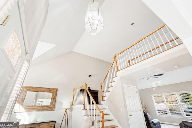 staircase featuring ceiling fan and high vaulted ceiling