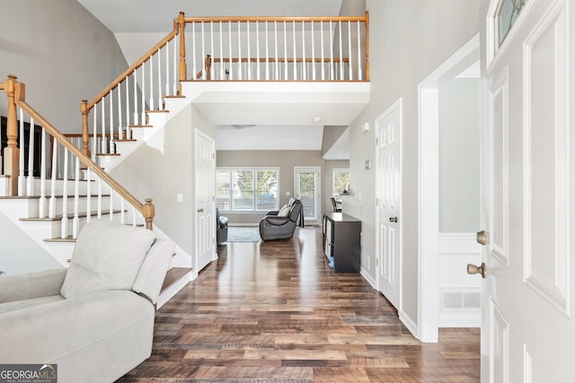 entrance foyer with dark hardwood / wood-style flooring and a towering ceiling