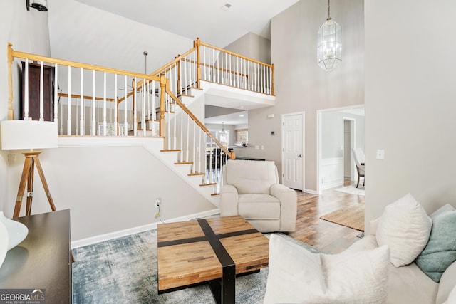 living room with an inviting chandelier, a towering ceiling, and hardwood / wood-style floors