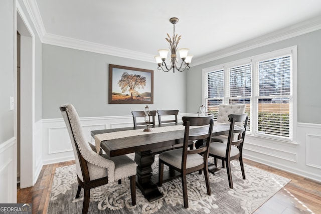 dining area with hardwood / wood-style flooring, crown molding, and a chandelier