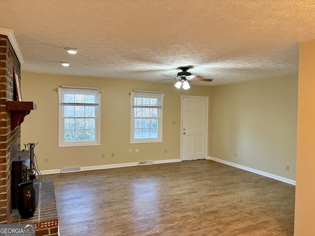 unfurnished living room featuring a brick fireplace, a textured ceiling, dark hardwood / wood-style floors, and ceiling fan