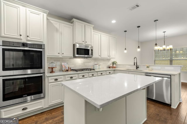 kitchen featuring stainless steel appliances, kitchen peninsula, sink, and white cabinets