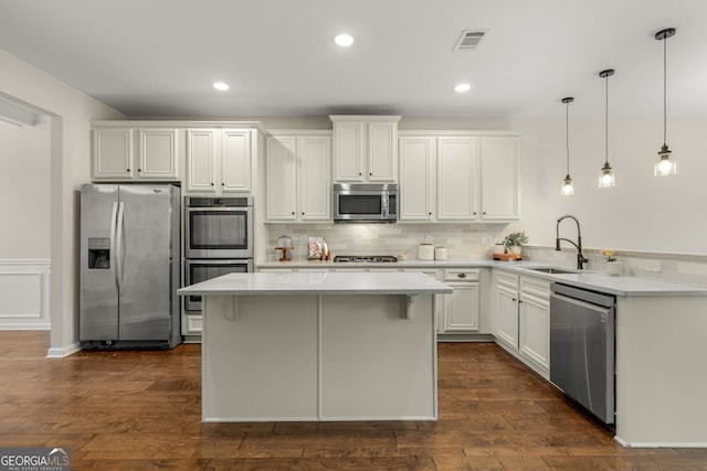 kitchen featuring pendant lighting, sink, appliances with stainless steel finishes, white cabinetry, and dark hardwood / wood-style floors