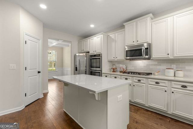 kitchen with white cabinetry, dark hardwood / wood-style flooring, a kitchen island, and appliances with stainless steel finishes