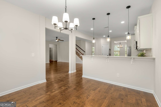 kitchen with hanging light fixtures, white cabinets, a kitchen breakfast bar, and kitchen peninsula