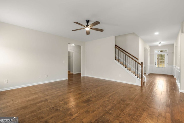 unfurnished living room featuring dark wood-type flooring and ceiling fan