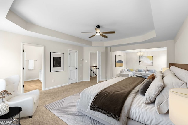 carpeted bedroom with ceiling fan, ensuite bath, and a raised ceiling