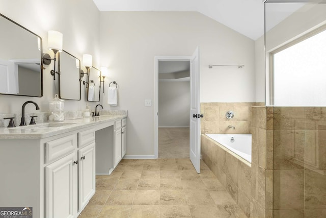 bathroom with lofted ceiling, vanity, and a relaxing tiled tub