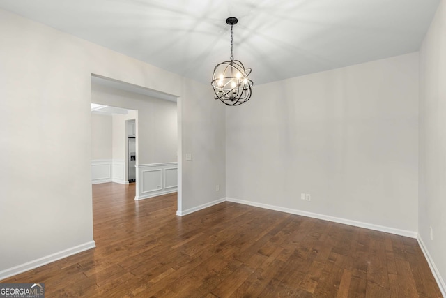 empty room with dark wood-type flooring and a notable chandelier