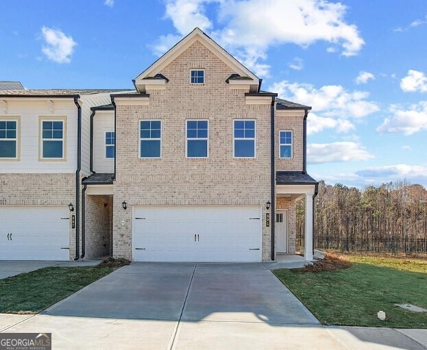 view of front facade featuring concrete driveway, brick siding, an attached garage, and a front yard