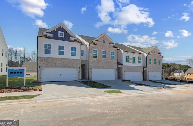 townhome / multi-family property featuring a garage, concrete driveway, and brick siding