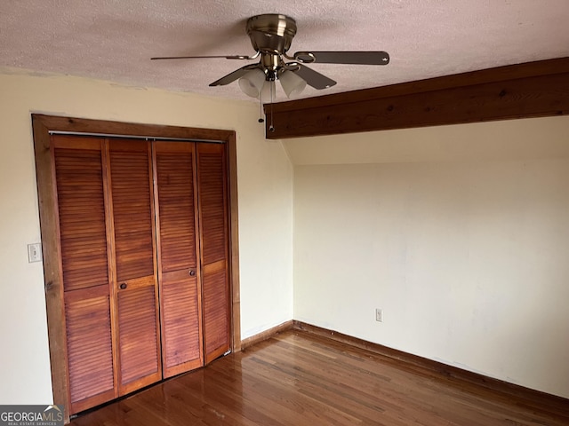 unfurnished bedroom with a textured ceiling, wood-type flooring, a closet, vaulted ceiling, and ceiling fan