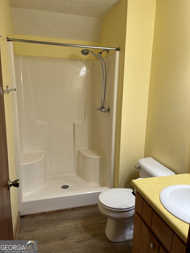 bathroom featuring a textured ceiling, toilet, hardwood / wood-style flooring, and a shower