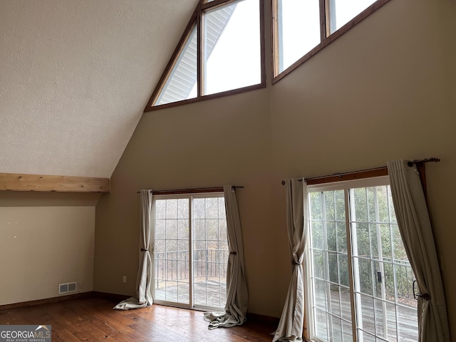 unfurnished living room featuring hardwood / wood-style flooring and a towering ceiling