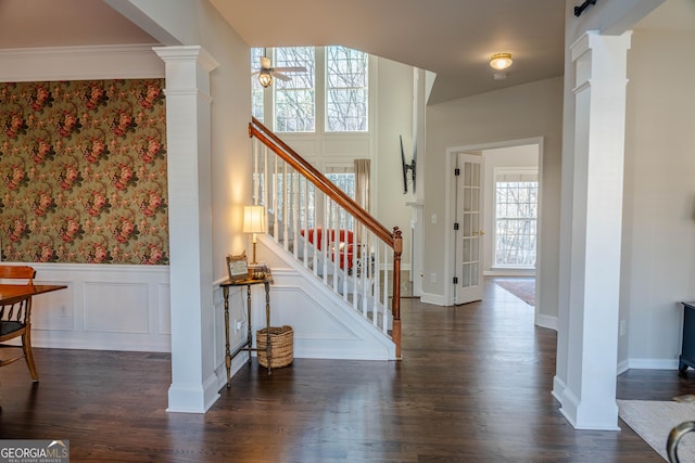 foyer featuring ceiling fan, dark wood-type flooring, ornate columns, and a barn door