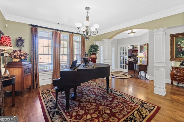 misc room with hardwood / wood-style flooring, ornamental molding, an inviting chandelier, and ornate columns