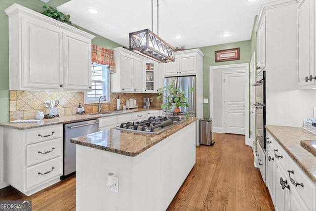 kitchen with sink, hanging light fixtures, stainless steel appliances, a center island, and white cabinets