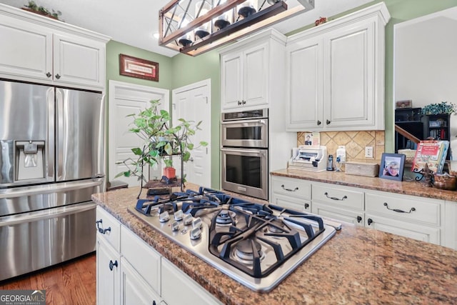 kitchen with stone counters, white cabinetry, appliances with stainless steel finishes, and decorative backsplash