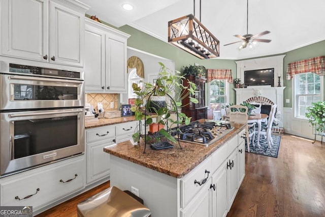 kitchen featuring dark stone countertops, dark hardwood / wood-style floors, a kitchen island, stainless steel appliances, and white cabinets