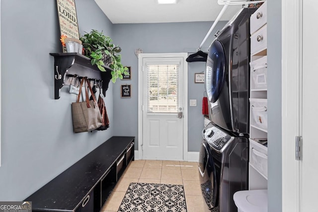 mudroom with light tile patterned floors and stacked washing maching and dryer