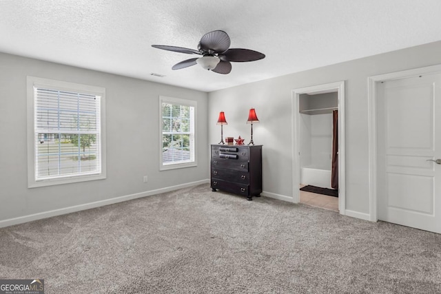 unfurnished bedroom with ceiling fan, light colored carpet, a textured ceiling, and ensuite bathroom