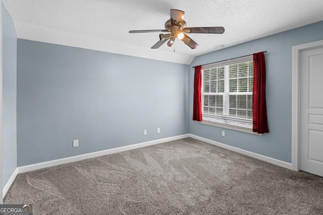 spare room featuring ceiling fan, vaulted ceiling, a textured ceiling, and carpet