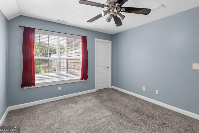 carpeted empty room with ceiling fan, vaulted ceiling, and a textured ceiling