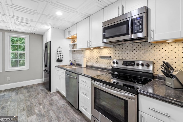 kitchen with sink, decorative backsplash, white cabinets, and appliances with stainless steel finishes