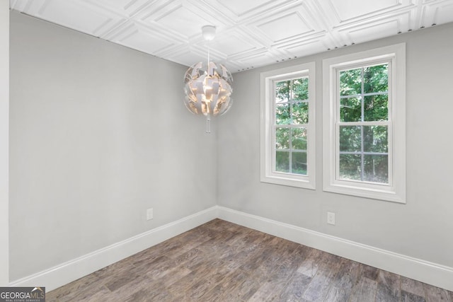 empty room featuring wood-type flooring and a chandelier