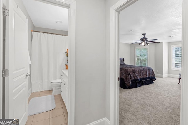 carpeted bedroom with ceiling fan, a textured ceiling, and ensuite bath