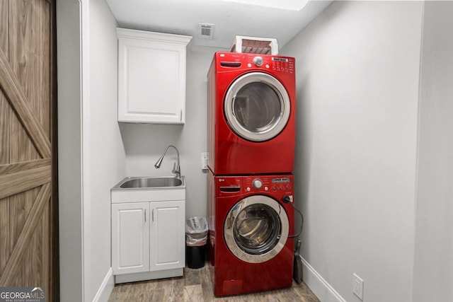 washroom with light hardwood / wood-style floors, stacked washer and dryer, cabinets, and sink