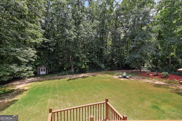 view of yard with a storage shed, a wooden deck, and an outdoor fire pit