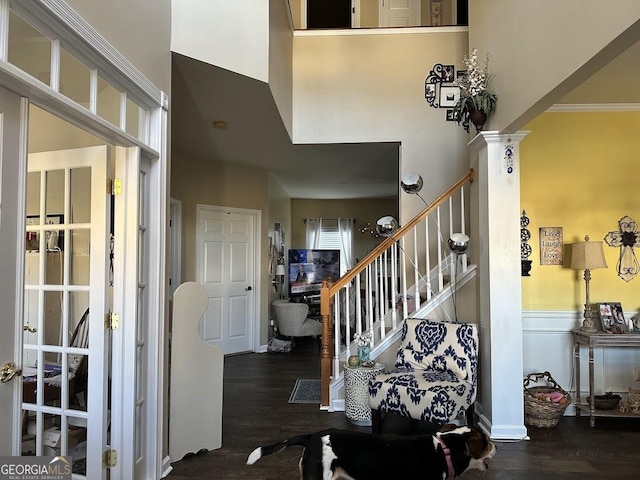 stairway with decorative columns, a high ceiling, and wood finished floors