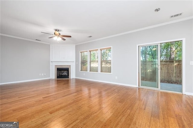 unfurnished living room with light hardwood / wood-style floors, a wealth of natural light, and ornamental molding