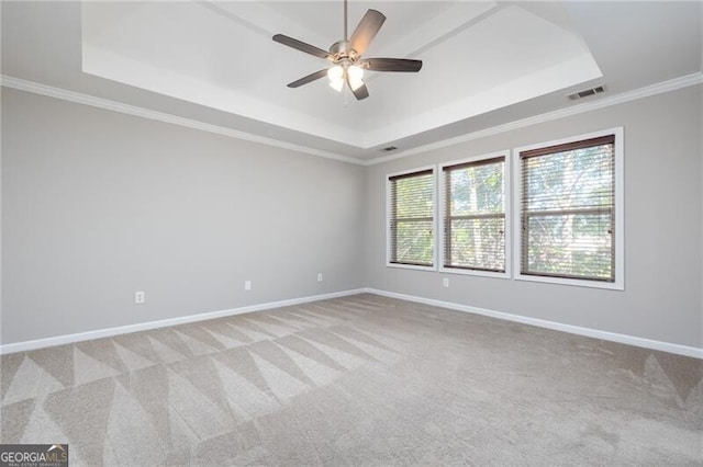 carpeted empty room featuring crown molding, plenty of natural light, ceiling fan, and a raised ceiling