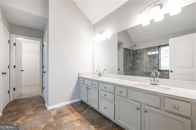 bathroom with a tile shower, lofted ceiling, and vanity