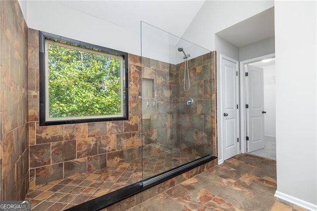 bathroom featuring a tile shower and vaulted ceiling